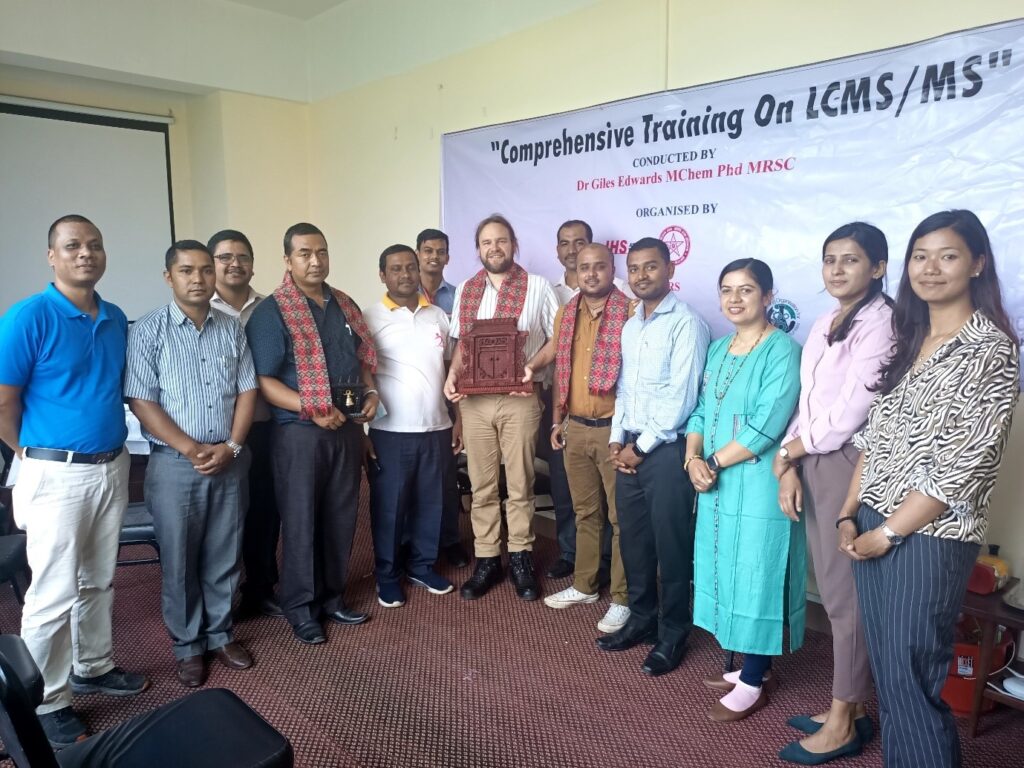 A group of people with Giles at the centre holding a Nepalese Khata.