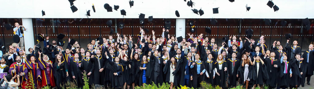 Large group of graduating students throwing hats into the air