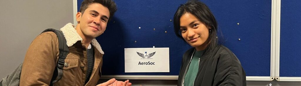 Two people standing either side of a laptop screen which says Aerosoc