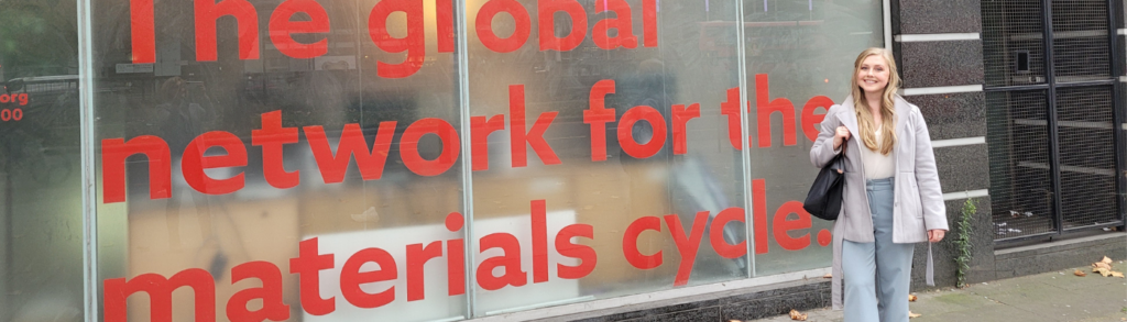 Woman smiling in front of sign that says The Global Network for the Materials Cycle