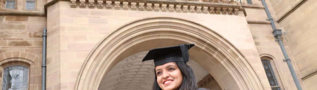 Woman in graduation robes outside main university building