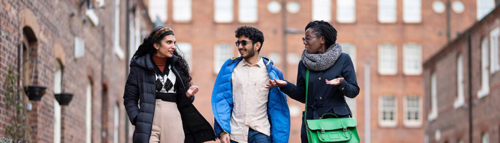 Two women either side of a man walking down a city street