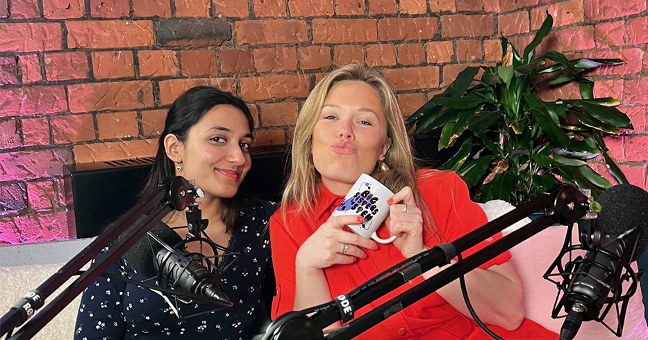 Two women posing humorously for the camera, behind microphones