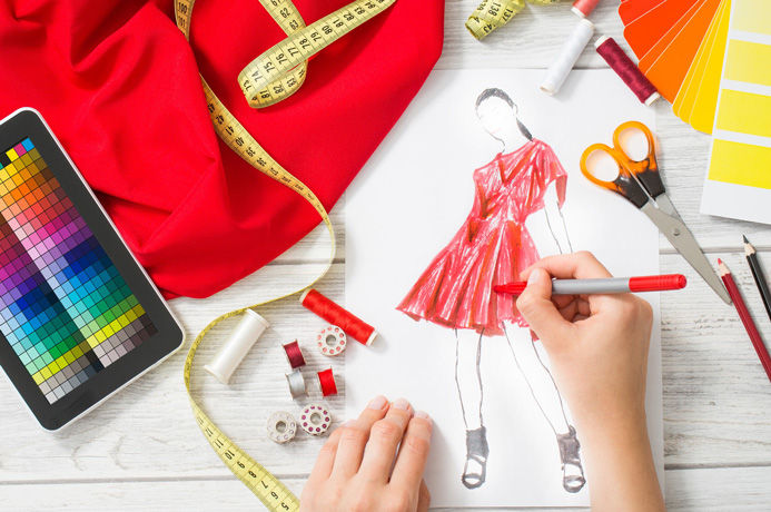 Person designing fashion clothes surround by sewing materials